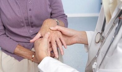 o doutor examina as articulacións das mans con artrose e artrite